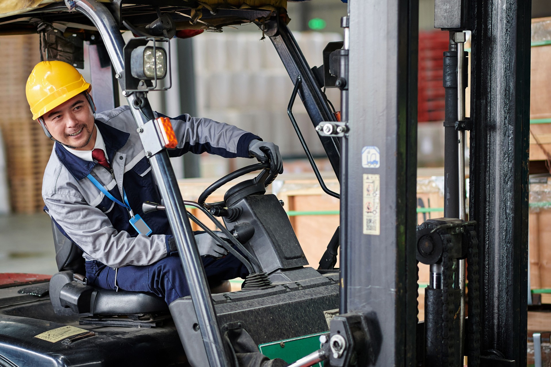 Side View of Asian Warehouse Worker Driving Forklift